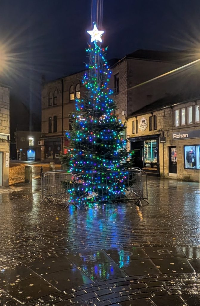 A photograph of St George's Square showing the Christmas tree illuminated against the night sky.